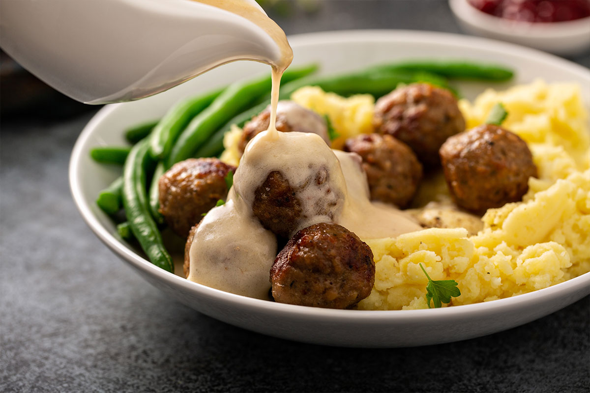 Homemade Swedish meatballs served with mashed potatoes and crisp green beans, all smothered in gravy